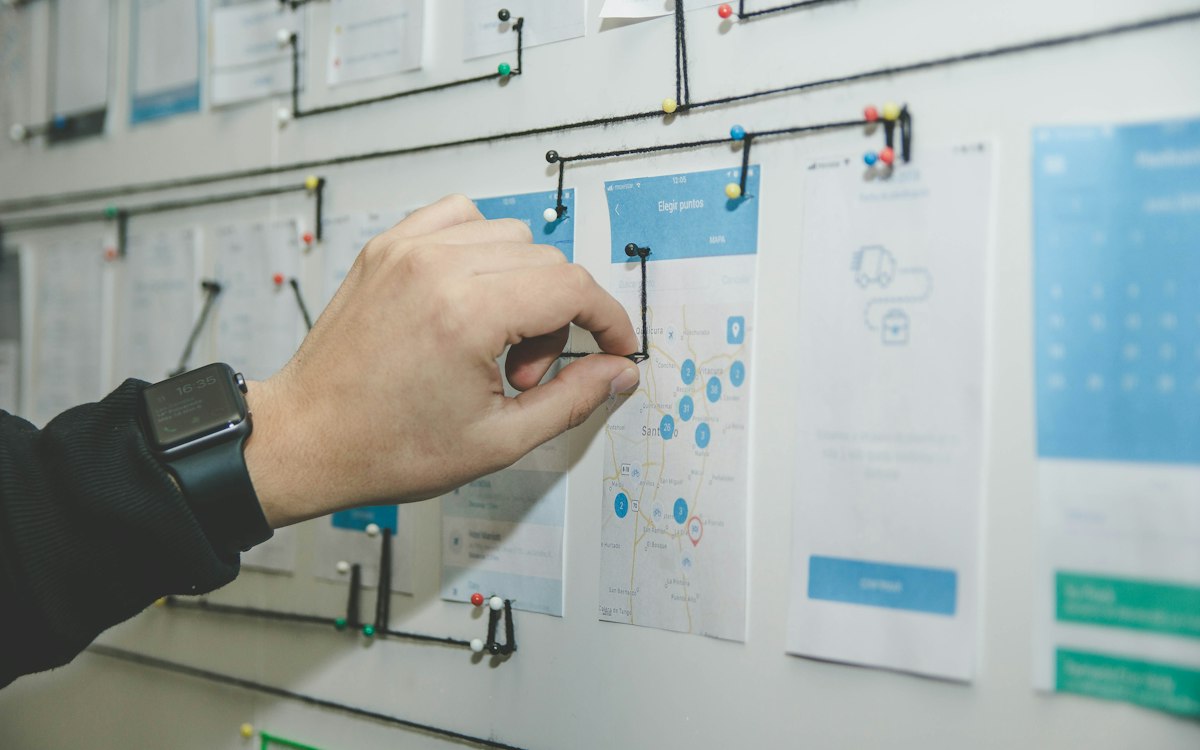 A hand arranging task notes on a planning board.