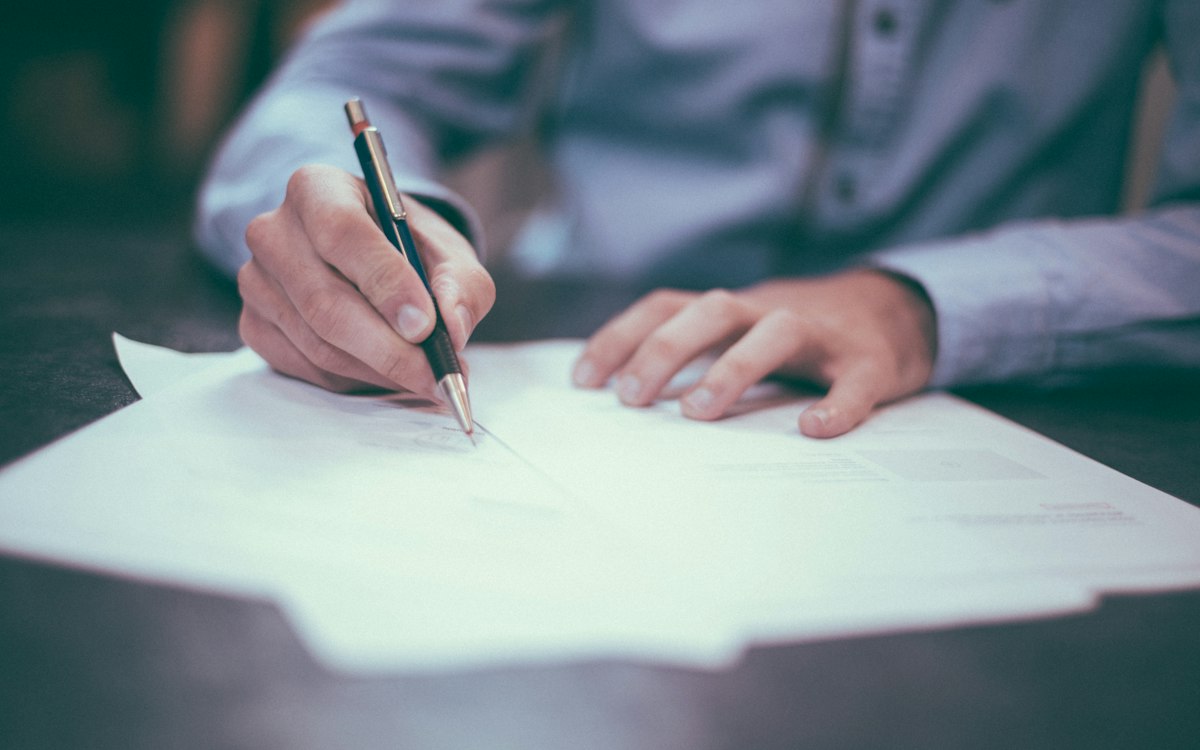 A person working through notes on a sheet of paper.